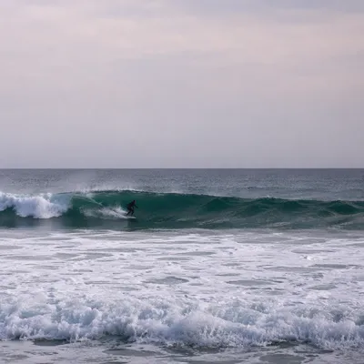 Distant Surfer Riding Teal Ocean Wave