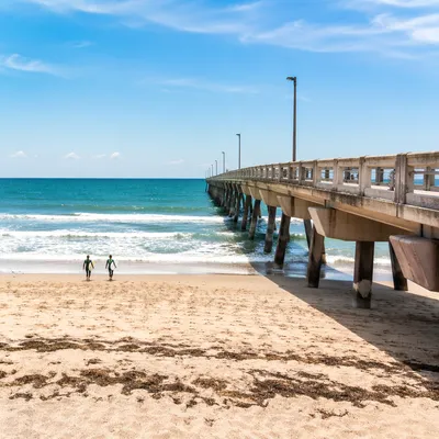 Distant Surfers by Summer Ocean Pier