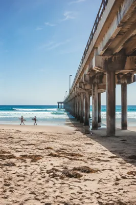Distant Surfers by Summer Ocean Pier
