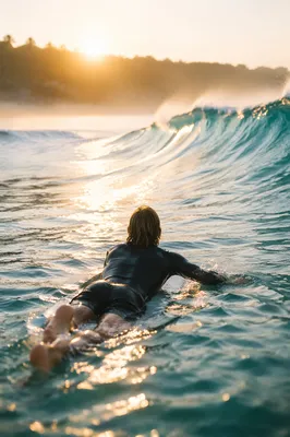 Surfer Paddling Toward Sunrise Ocean Wave
