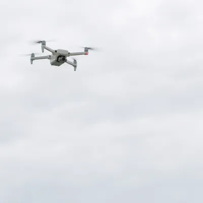 White Drone Hovering in Overcast Sky