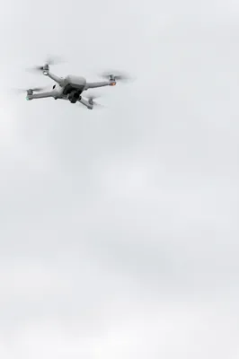 White Drone Hovering in Overcast Sky