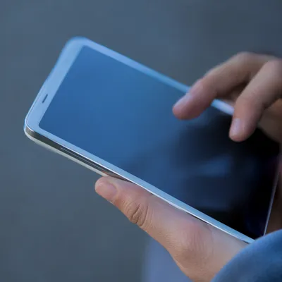 Hands Holding Smartphone With Blank Blue Screen