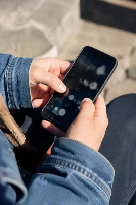 Hands Holding Smartphone in Sunlit Outdoor Closeup