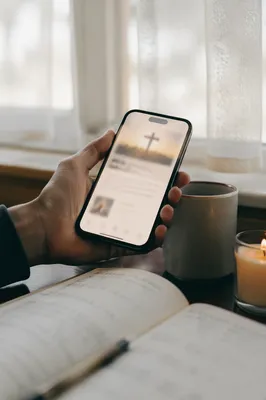 Hand Holding Smartphone by Window Desk