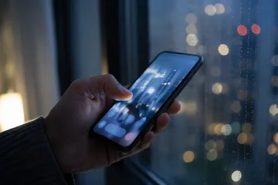 Hand Holding Smartphone by Rainy Window