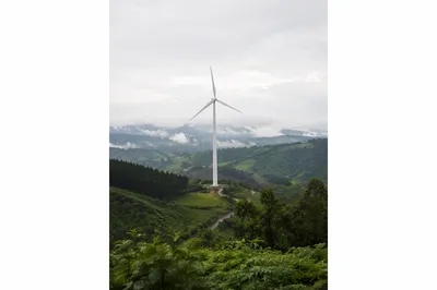 White Wind Turbine Over Misty Green Hills