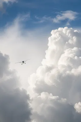Small Airplane Flying Through Towering Clouds