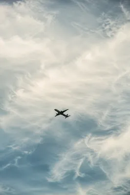 Airplane Silhouette Gliding Through Clouded Sky