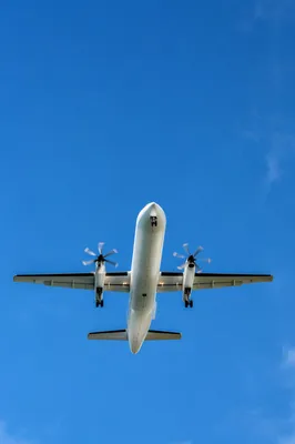 White Turboprop Airplane Crossing Clear Blue Sky