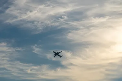 Airplane Silhouette Through Wispy Clouded Sky