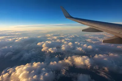 Airplane Wing Above Sunlit Cloudscape