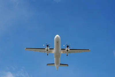 White Turboprop Airplane Crossing Clear Blue Sky