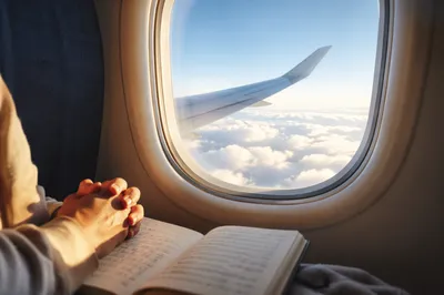 Prayerful Airplane Journey Above Morning Clouds