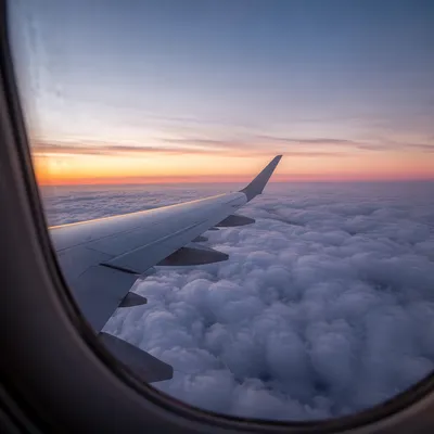 Airplane Wing Above Clouds at Sunrise