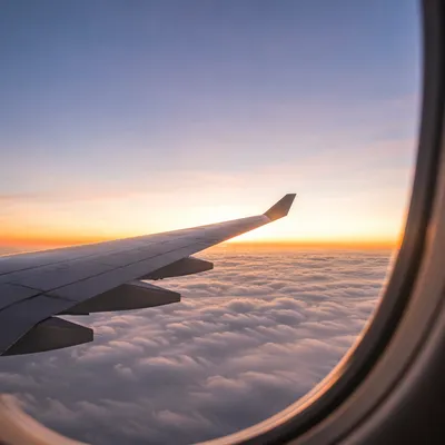 Airplane Wing Above Clouds at Sunrise