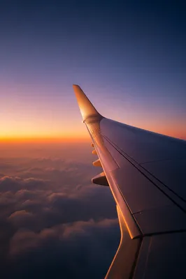 Airplane Wing Above Clouds at Sunrise