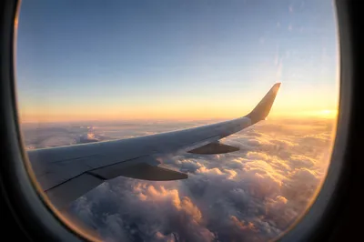 Airplane Wing Above Clouds at Sunrise