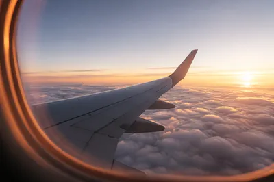 Airplane Wing Above Clouds at Sunrise