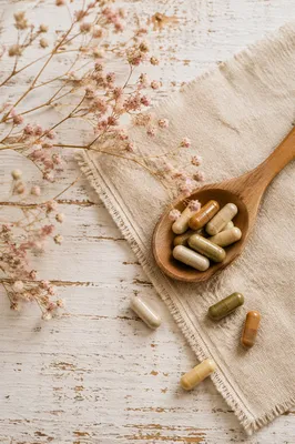 Natural Herbal Capsules on Rustic Wooden Spoon