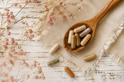 Natural Herbal Capsules in Rustic Wooden Spoon
