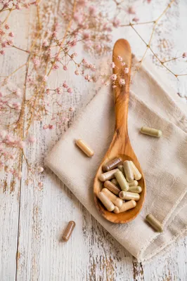 Natural Herbal Capsules on Rustic Wooden Spoon